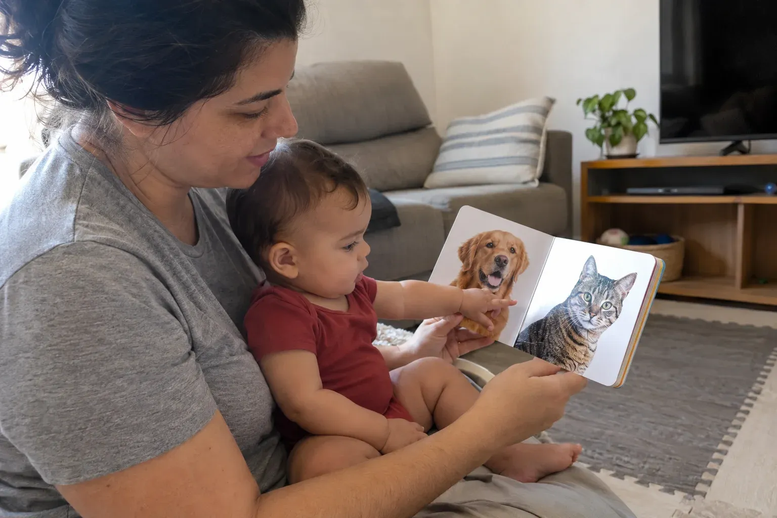 Mãe e bebê olhando juntos um livro com imagens de cachorro e gato.