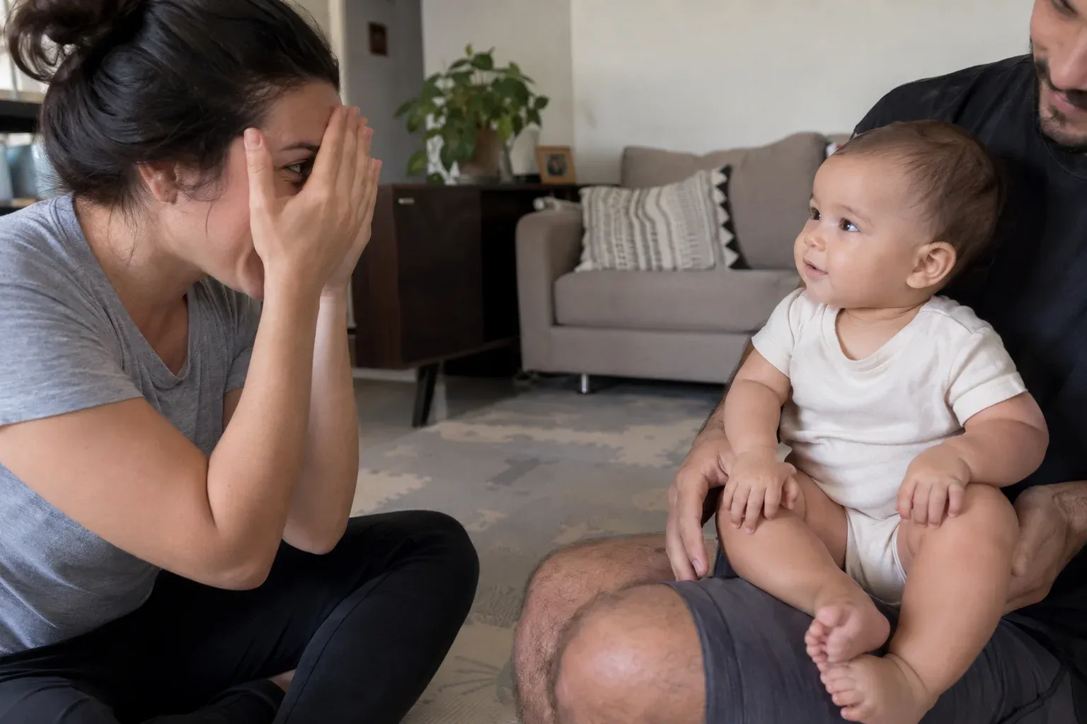 Mãe cobrindo o próprio rosto com as mãos na brincadeira de cadê e achou, com o bebê no colo do pai.
